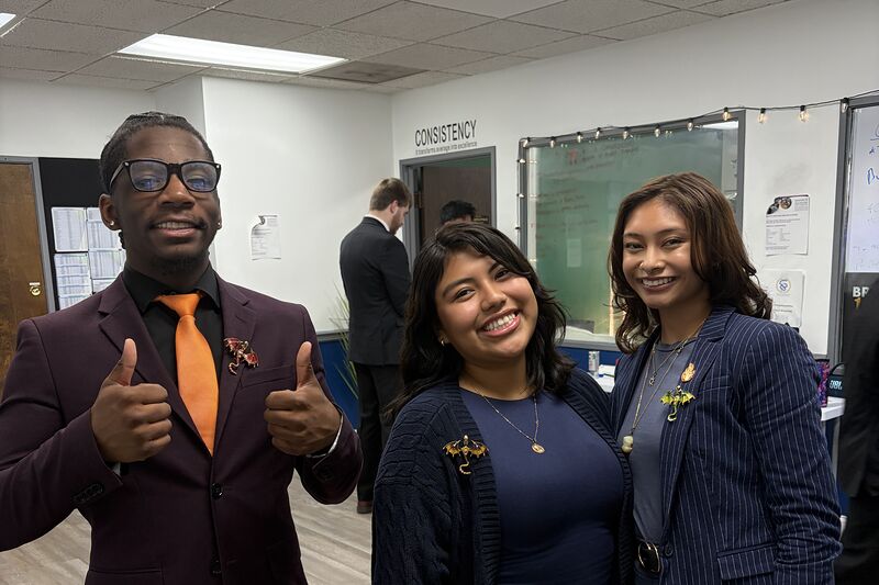 Three Valorix Agency team members in the office, one giving a thumbs up beside the team boards